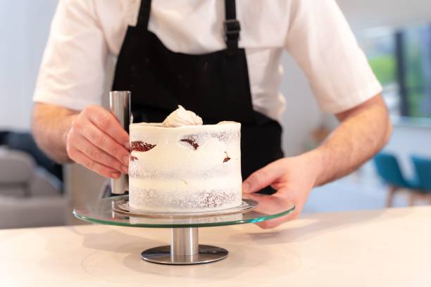 istock A man cooking a red velvet cake, perfecting the circle adding cream with a smoothing spatula 1459565432