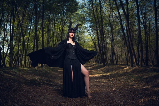 A gothic girl with Maleficent horns posing in a mystic forest