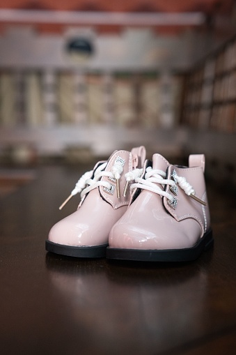 A vertical closeup of a pair of child shoes on the wooden surface.