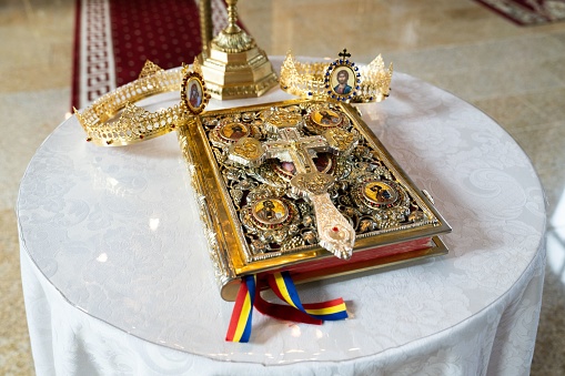 A golden crown on an Antique Holy Bible with golden precious covers on a table, wedding comcept