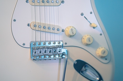A closeup of Electric guitar bridge and strings against blurred background