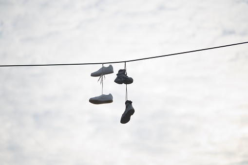 A low angle shot of a pair of shoes dangling from a wire