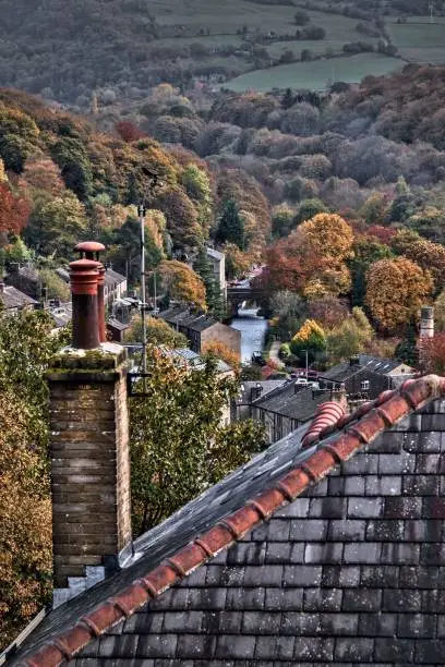 A vertical shot of Hebden Bridge market-town with old buildings surrounded by autumn trees