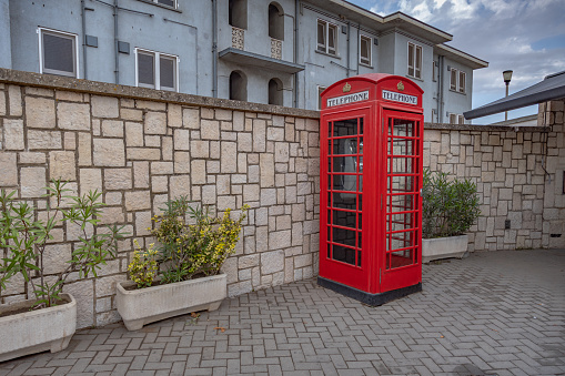 Gibraltar cityscape. Close up of empty typical English red telephone box close to Gibraltar Passport Control Station.