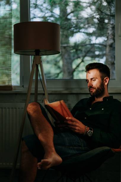 istock Young Caucasian male reading book at home 1459575475