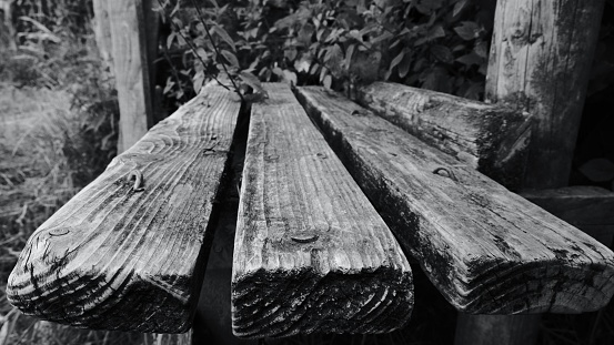 A grayscale of an old wooden bench with details outdoors