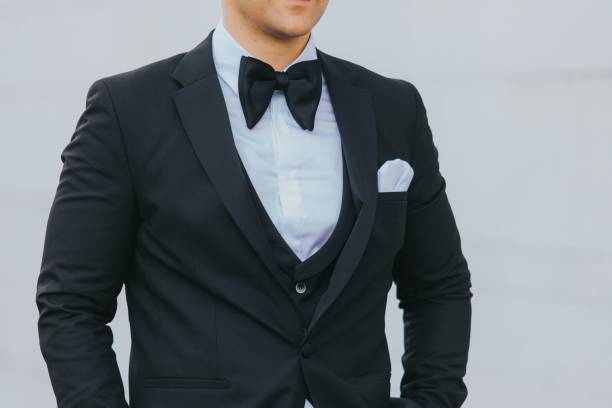 istock Man in a black suit, white shirt with black bow tie against a white background 1459576498