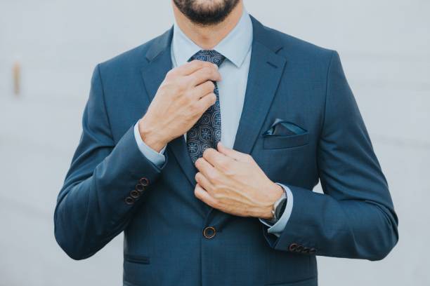 istock Man in a blue business suit fixing his blue tie 1459576607
