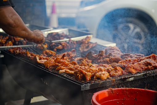 Chicken parts on the grill with fire flames and smokes.  Selective focus.