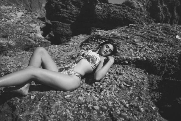 istock Beautiful woman in a bikini lying on rocks 1459578418
