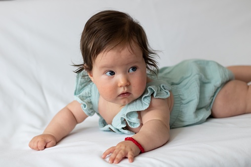 A close-up shot of a cute baby toddler on a white fabric