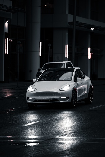 Calgary, Canada – May 11, 2022: A vertical closeup of a white Tesla driving on the pet roads in the streets
