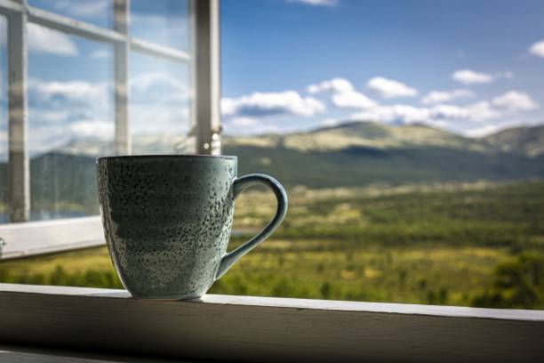 istock Green mug of coffee and mountain view through an open window 1459584236