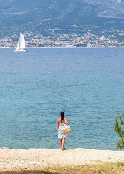 istock Back view of a young female standing on Bene beach in Split, Croatia 1459584449