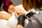 Manicure painting process. Manicure master paint the nails with transparent varnish in a nail salon, close up.