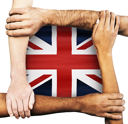 Multiracial group of hands and arms of men and women clasping each other, signifying unity, solidarity, cooperation and teamwork, around the Union Jack.
