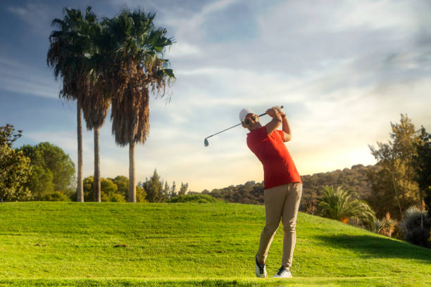 colpo di golf uomo. swing da golf professionale. giocatore di golf che si allontana. vista frontale del golfista che termina lo swing con un sorriso. lunghezza intera del golfista che gioca sul campo. golfista che colpisce il colpo di golf con la mazza - golf swing golf golf club chipping foto e immagini stock