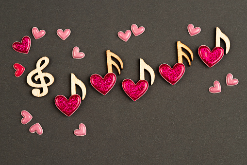 Musical wooden notes with hearts, top view.