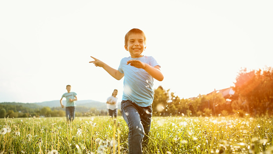 Smiling children playing in meadow against sky during sunset.