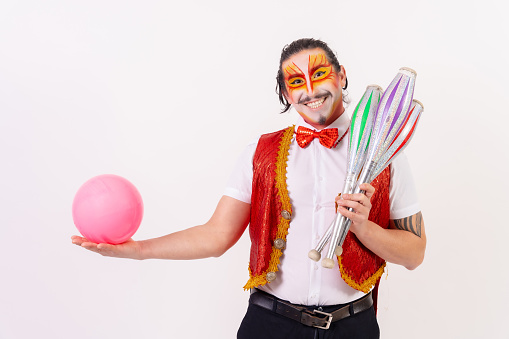 Portrait of a juggler smiling with juggling mallets and a ball isolated on white background