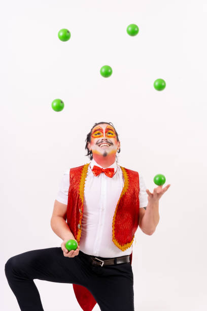 Smiling juggler juggling green balls isolated on white background