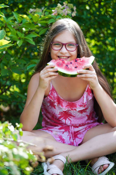 笑い、食べ、スイカを楽しむ若い女の子の接写。 - children only healthy lifestyle vertical close up ストックフォトと画像