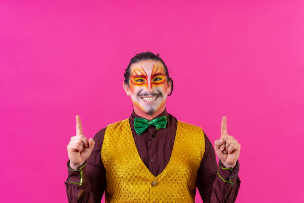 Clown with white face makeup showing empty space on pink background, announcing something, pointing up