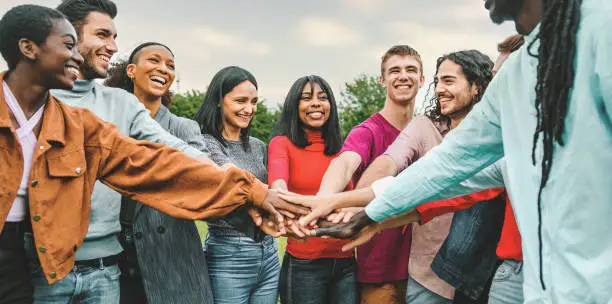 joyful team of multi-ethnic young people friends joining hands together - diversity, unity, trust, oneness, international youth culture concept - interracial person connecting together
