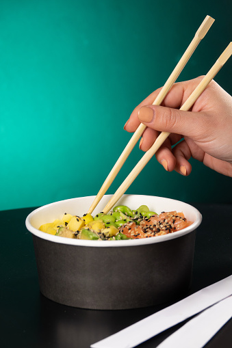 Poke box and chopsticks on a color background