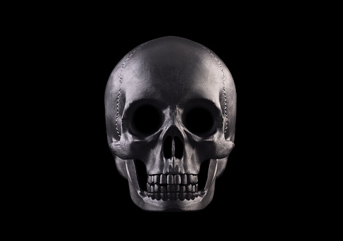 Human skeleton skull in dramatic low key light, corona covid-19 against pitch black background