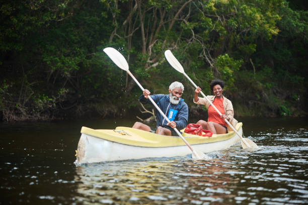 Smiling couple paddling their double canoe along a river