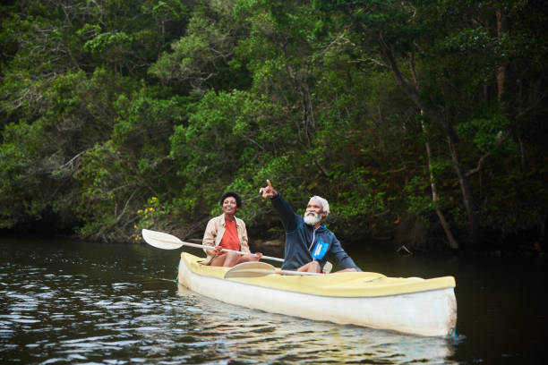 istock Smiling couple looking at the view from their double canoe on a river 1459604266