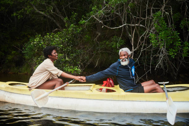 istock Smiling couple holding hands while floating along a river in a double canoe 1459604533