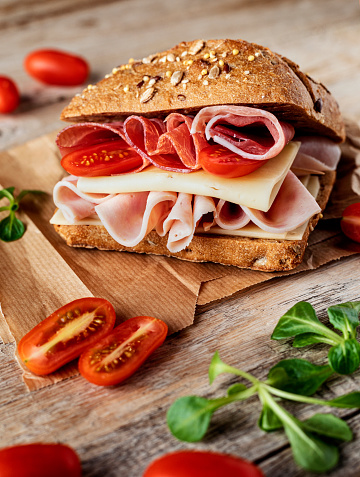 A delicious sandwich made from homemade bread with ham, prosciutto, cheese and vegetables
