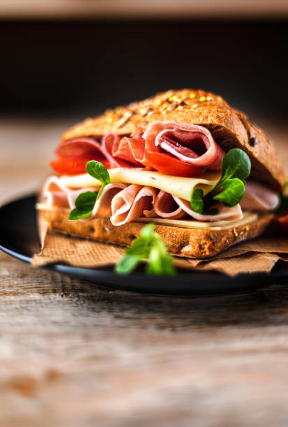 A delicious sandwich with ham, prosciutto, cheese and vegetables A delicious sandwich made from homemade bread with ham, prosciutto, cheese and vegetables ciabatta stock pictures, royalty-free photos & images