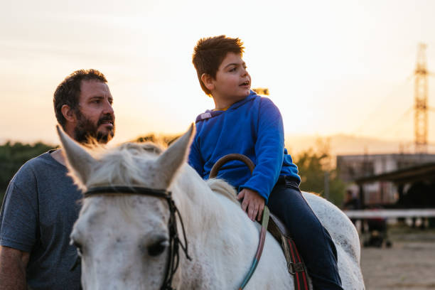 istock Boy with cerebral palsy and therapist in equine therapy session 1459608014