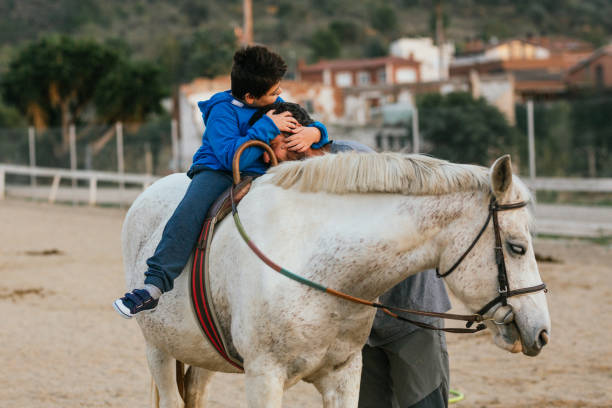 istock boy with disability embracing his physiotherapist during equine therapy session 1459608924