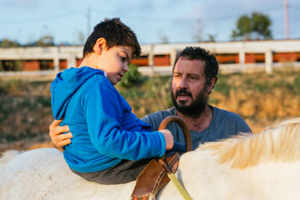 istock Child performing upper trunk exercises during equine therapy 1459609709