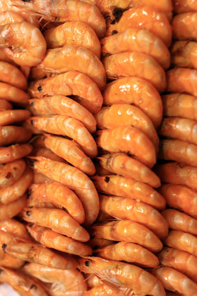 Shrimp are arranged on a bed of ice in a bustling seafood market.