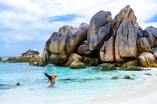 Women swimming at Anse Cocos beach with huge granite boulders at La Digue Seychelles Islands.