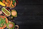 Assorted take out or delivery foods, above view side border on a dark wood background