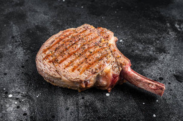 istock BBQ Grilled Tomahawk  beef veal steak on butcher table. Black background. Top view 1459616979