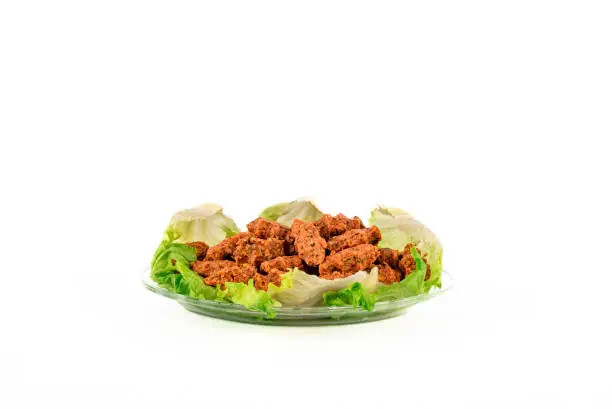 Photo of Turkish vegan lentil balls with lettuce isolated on glass plate.