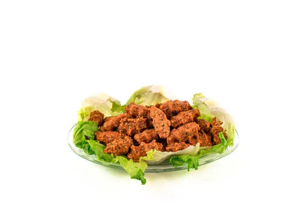 Photo of Close up Turkish vegan lentil balls with lettuce isolated on glass plate.