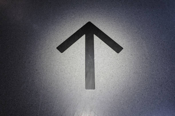 Black directional arrow on the ground with spotlight.