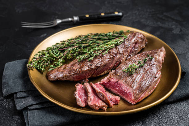 BBQ grilled Bavette Bavet beef meat steak with herbs on a plate. Black background. Top view BBQ grilled Bavette Bavet beef meat steak with herbs on a plate. Black background. Top view. flank steak stock pictures, royalty-free photos & images