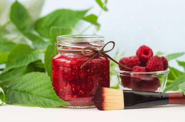 Raspberry mask (scrub) in a small glass jar and make-up brush. Homemade face or eye mask, natural beauty treatment and spa recipe. Copy space. Raspberry mask (scrub) in a small glass jar and make-up brush. Homemade face or eye mask, natural beauty treatment and spa recipe. Copy space. raspberry jam stock pictures, royalty-free photos & images