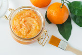 Orange clementine fruit mask (scrub) in a glass jar. Homemade face or body mask, natural beauty treatment and spa recipe. Top view.