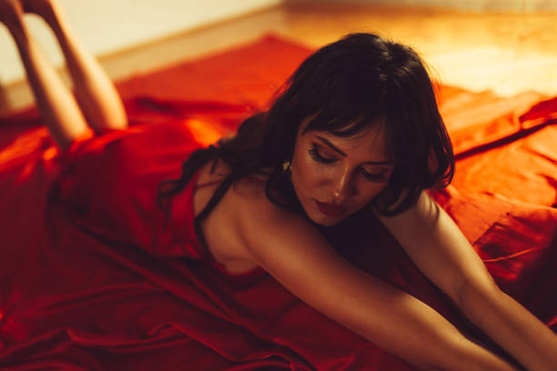 istock Young Woman Lying In Red Bed Sheets 1459622559