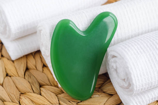 緑のグアシャマッサージストーン。アンチエイジング治療のための伝統的な漢方薬美容ツール。選択フォーカス。 - spooning ストックフォトと画像